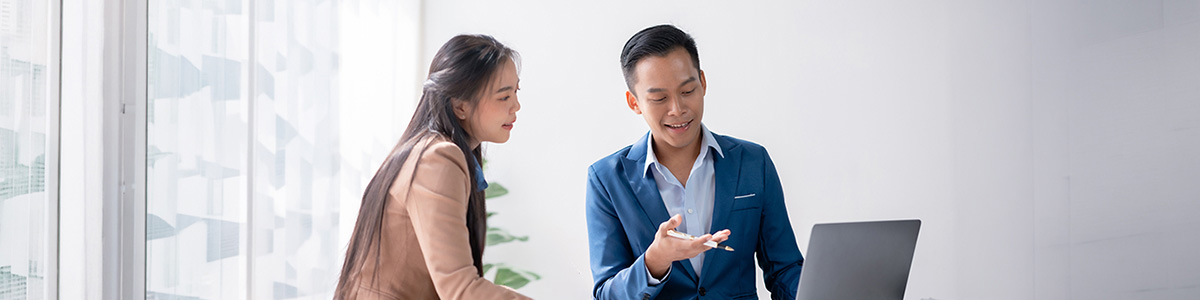 Two finance professionals reviewing a loan inquiry beside a laptop